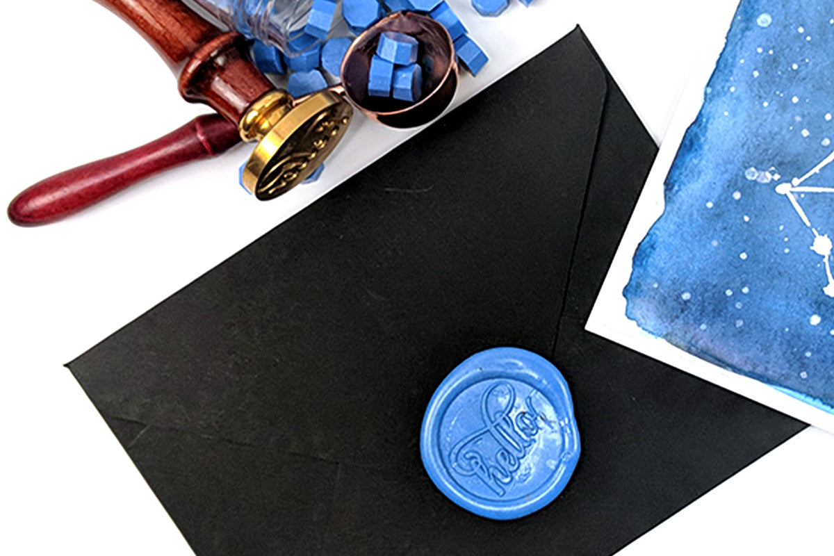 Black card envelope sealed with blue wax beads and Altenew's wax seal stamp