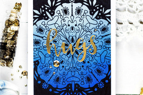 DIY hugs card with a hot foiled mandala design in the background and the sentiment "hugs"