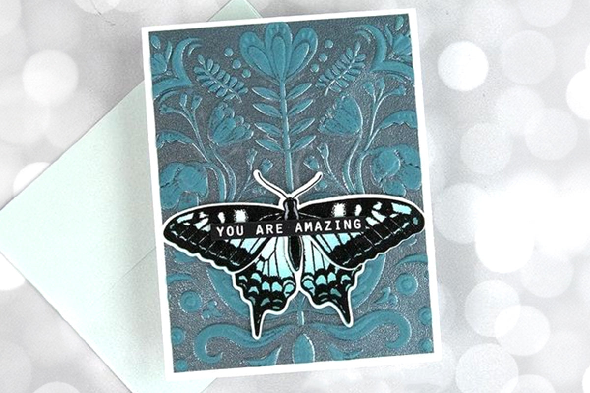 Handmade card with a 3D embossed whimsical motif background and a die-cut moth