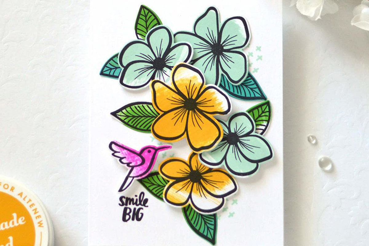 A colorful card with various flowers and a hummingbird as focal points, colored in with Altenew X Amy Tangerine Summer Dreams Fresh Dye Ink set
