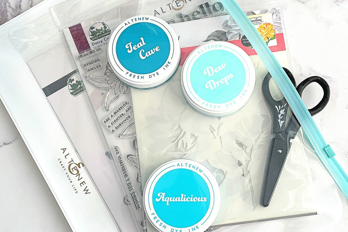 Altenew's Zip 'n' Keep craft storage pouch with an Altenew stamp set, stencil set, round ink pads, and a pair of scissors inside.