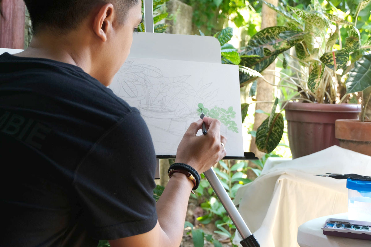 An artist painting outdoors and using plants and trees as inspiration