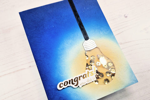 DIY congrats shaker card with a blue ink blended background and a light bulb design