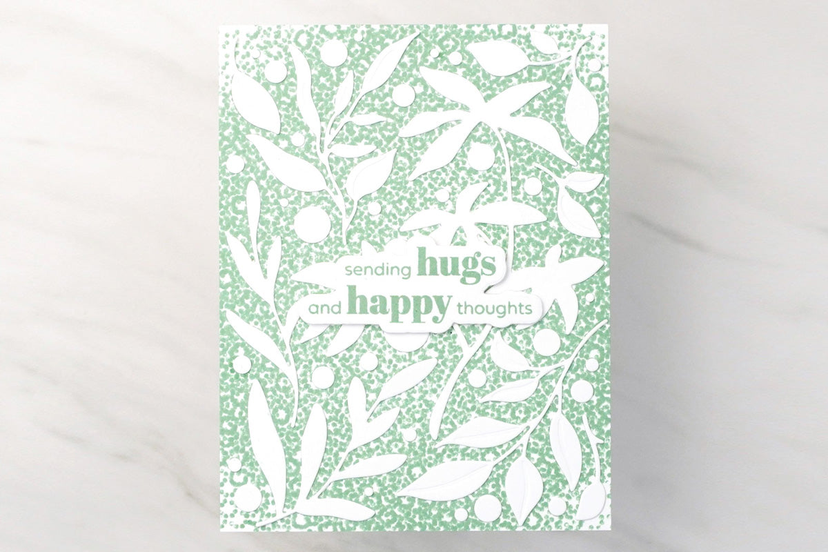 A green and white DIY card with a leafy background, made using zero waste craft tools