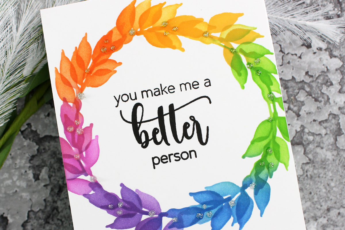 Simple greeting card with a leafy wreath in rainbow colors and the sentiment "you make me a better person"