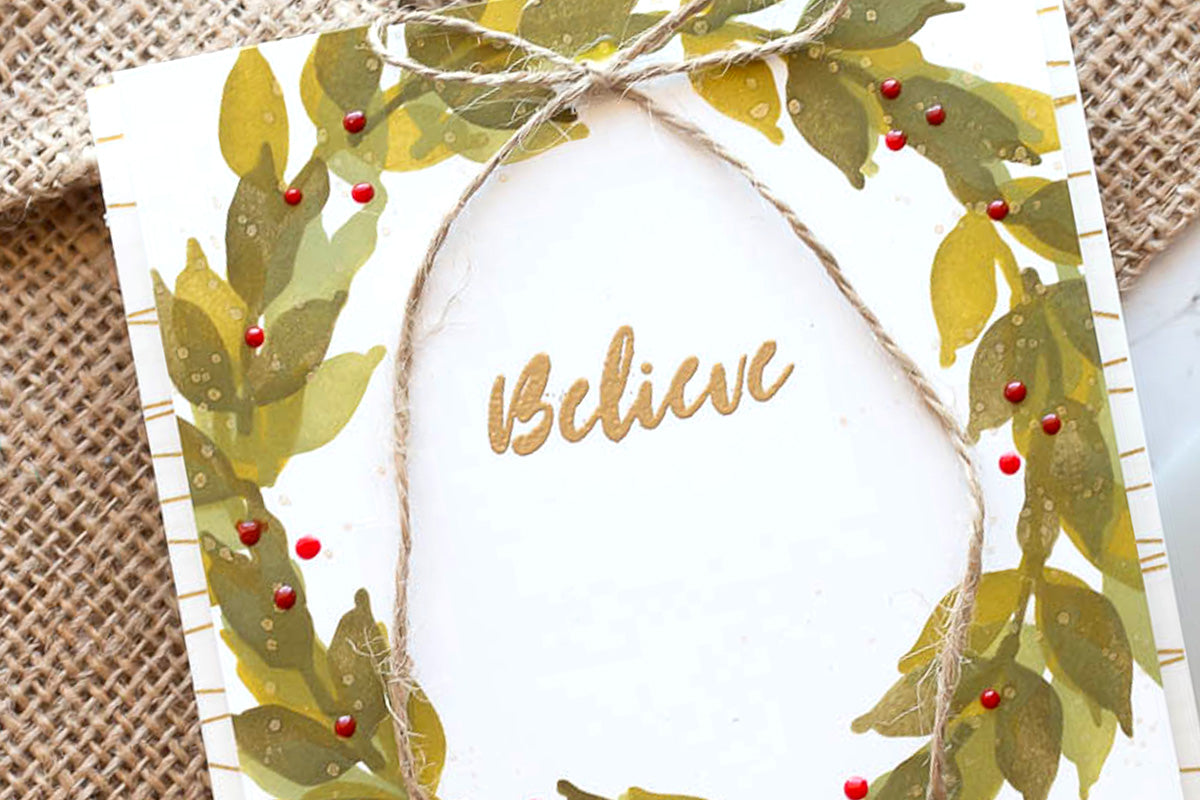 Seasonal handmade card with a wreath design, the sentiment "believe" and a twine tied into a ribbon