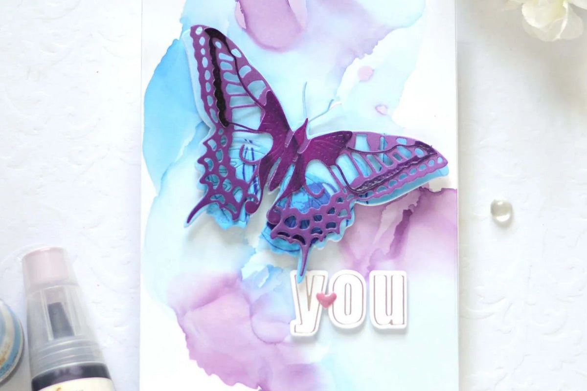 A card with a butterfly as a focal point, supplemented with letters from the Essential Alpha Set using the One-Go Paper Crafting System