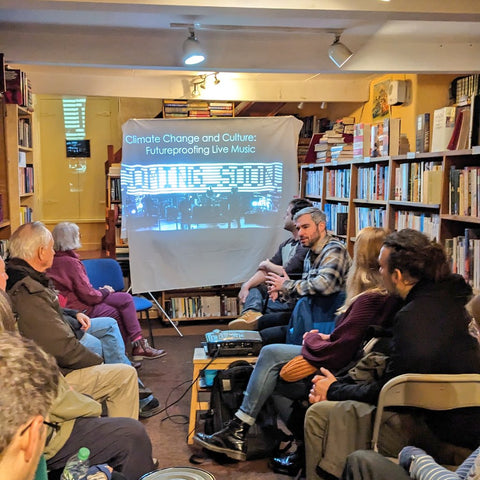 Climate scientist Chris Jones talking at an audience in the bookshop about his work with Massive Attack, speaking in front of a projection of his slides