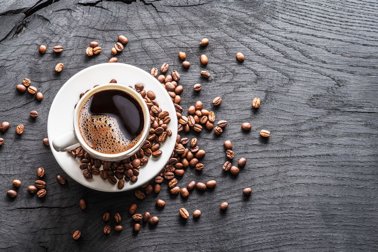 Eine Tasse duftender entkoffeinierter Kaffee von OHNE umrundet von Kaffeebohnen