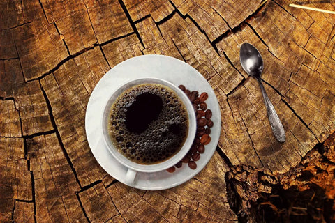 Tasse mit entkoffeiniertem Kaffee steht frisch gebrüht auf einem Baumstamm