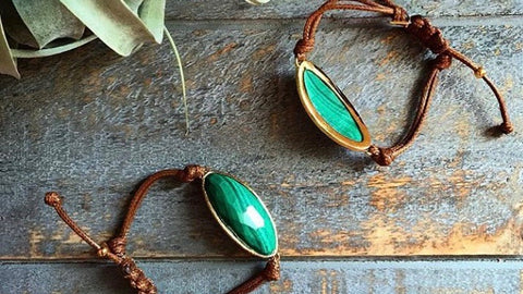 Lattice corded bracelets with malachite on wood table. 