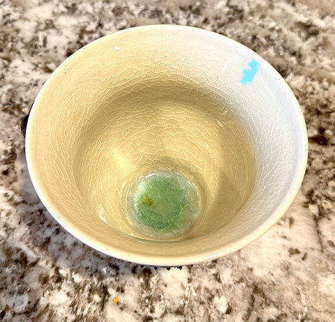 A cream bowl on a granite countertop. The bowl shows glaze crazing.