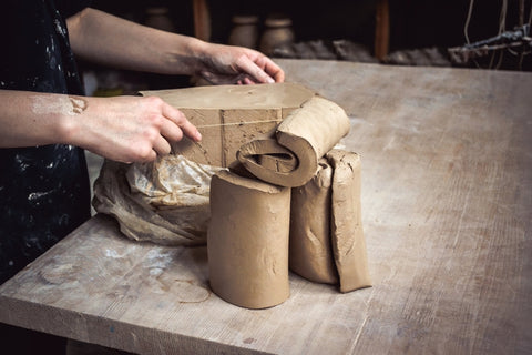 A pottery wedging clay in their home pottery studio