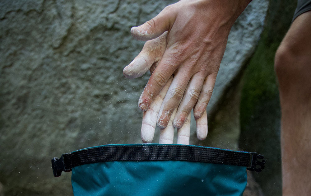 A boulderer removing his chalky hands from a bouldering bucket at Rubicon Crag in the Peak District