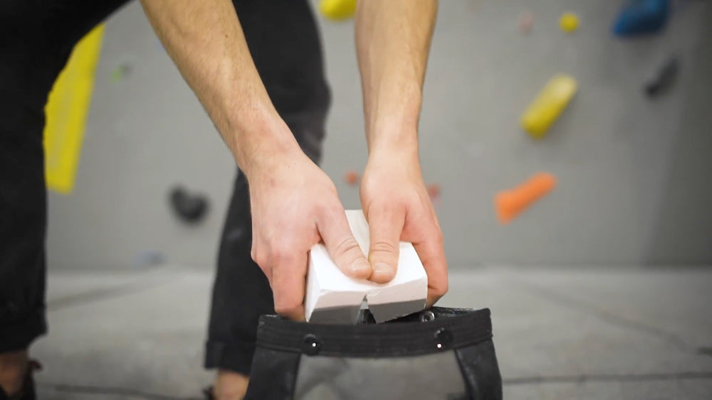 A boulderer breaking a chalk block into a bouldering bucket at Rockover Climbing Manchester