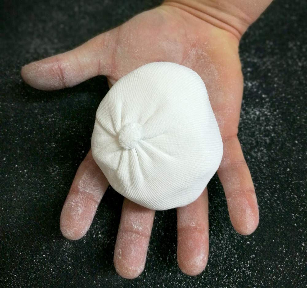 A climber's open hand holding a climbing chalk ball