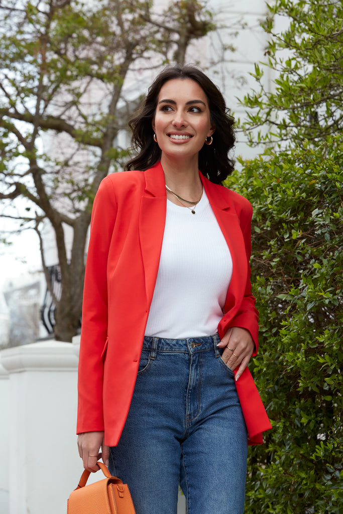 Woman Wearing Threadbare Red Tailored Relaxed Fit Blazer with a White Top, Blue Jeans and Orange Bag
