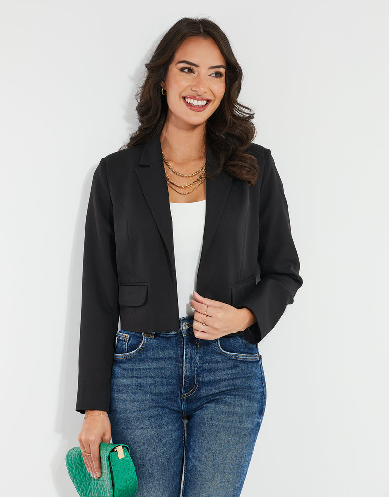 Woman wearing a Threadbare Black Cropped Short Length Blazer with a white bodysuit, jeans and a green bag