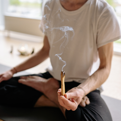 man meditating with palo santo stick burning