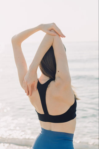 Girl performing triceps stretch as part of a 10 minute stretch routine.