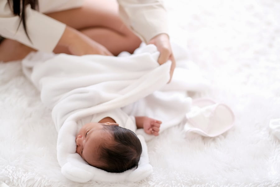 Newborn baby was swaddling with white cloth by her mother- Roll Up Baby