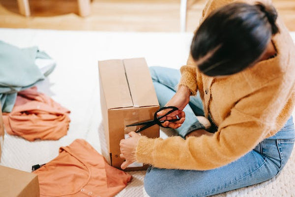 Woman cutting off adhesive tape from box with parcel