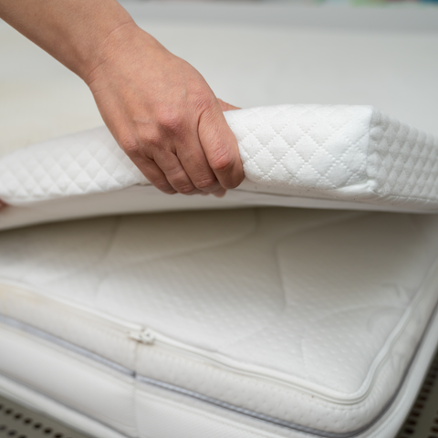 woman covering mattress with organic mattress topper