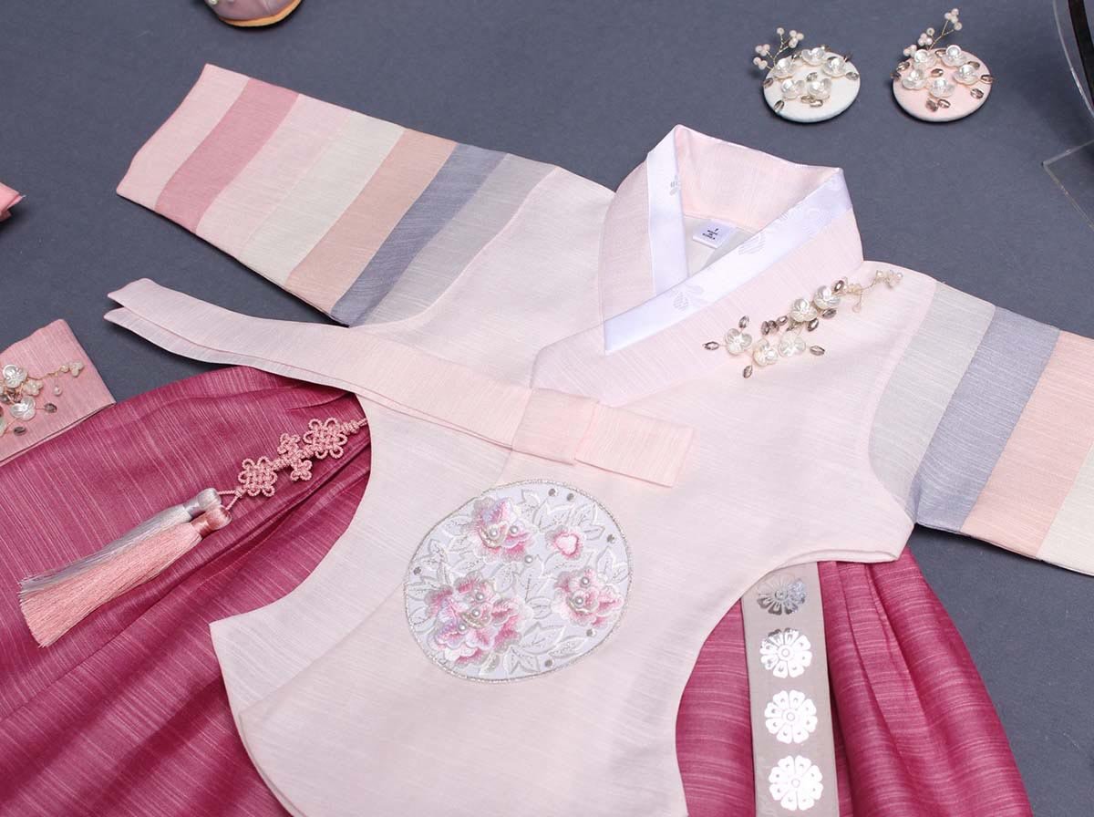 The Saekdong Jeogori adds a playful feel to the baby girl hanbok in dark pink and light pink.