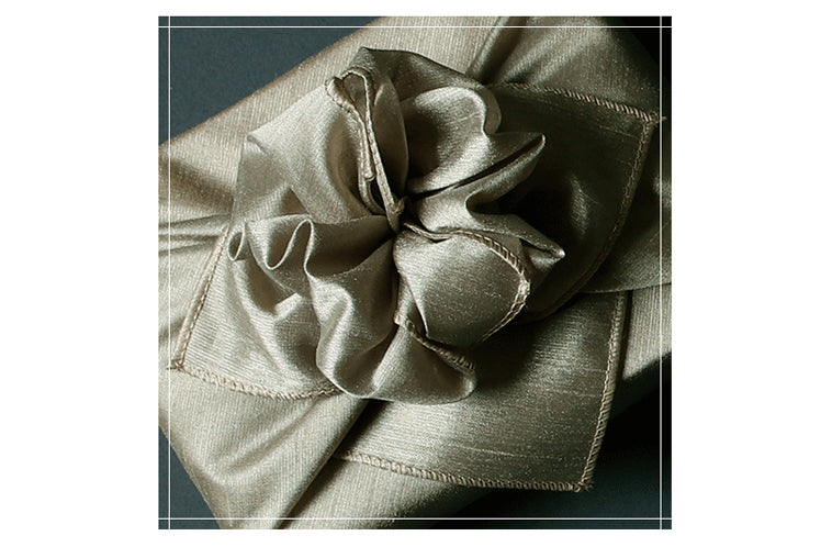 An intricate bow added to the top of the sage fabric wrapping paper turns this into Bojagi art.