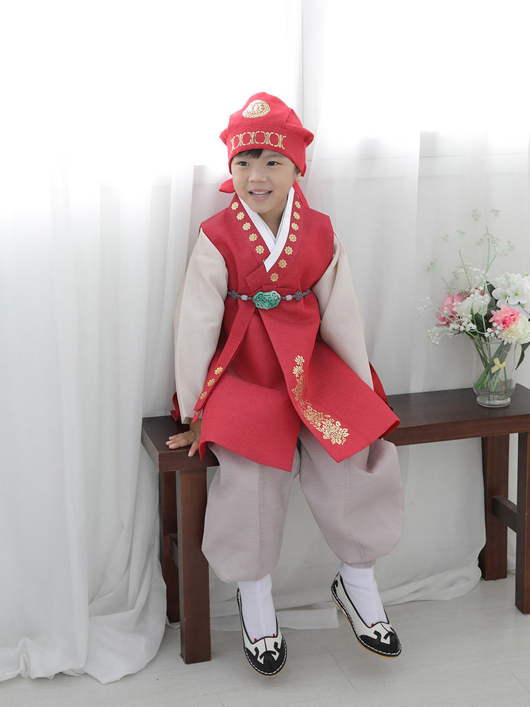 모델이 우리의Cute Doryung Boys Hanbok in Red입고 앉아있는 모습