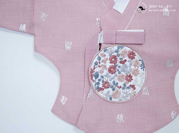 Close up view of the Pink Jeogori. The traditional Korean characters embroidered on it are of various. The embroidered floral patch in the middle enhance the look of the jeogori.