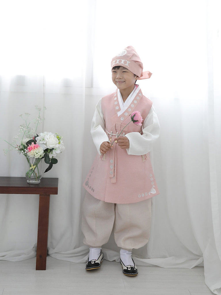 우리의 Soft Cream Boys Hanbok in Light Red를 입고 한 송이 꽃을 든 모델