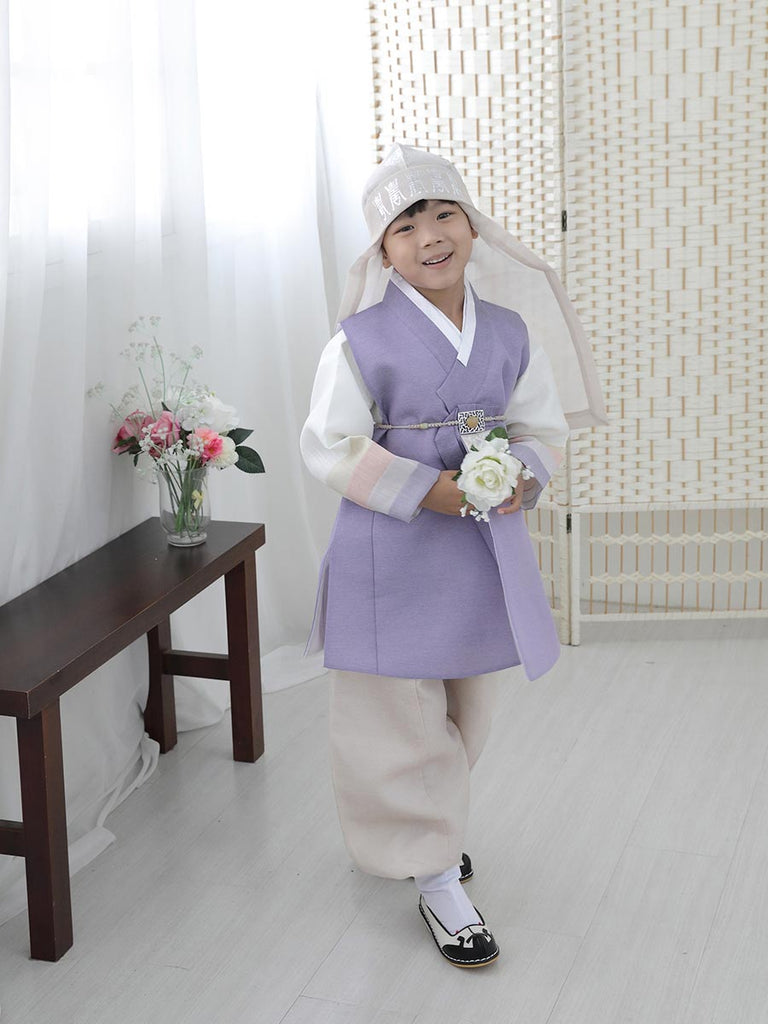 우리의 Spring Boys Hanbok in Pastel Lavender를 입고 꽃을 들고 서있는 소년