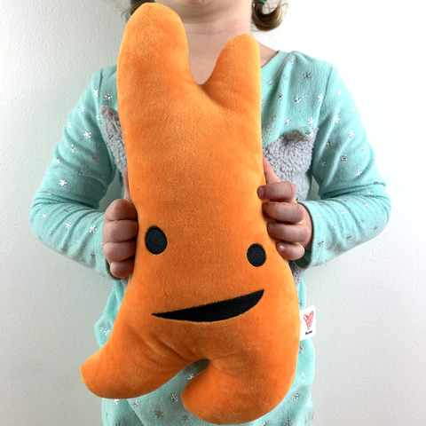 Photograph of child in light blue pajamas holding an orange thymus plush toy from I Heart Guts