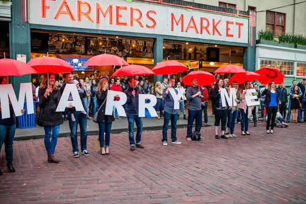 People holding "will you marry me" sign at Pike Place Market