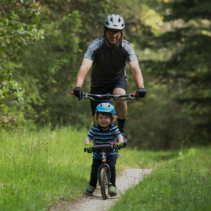 boy wearing giro scamp helmet for kids, cycling on a bicycle with father