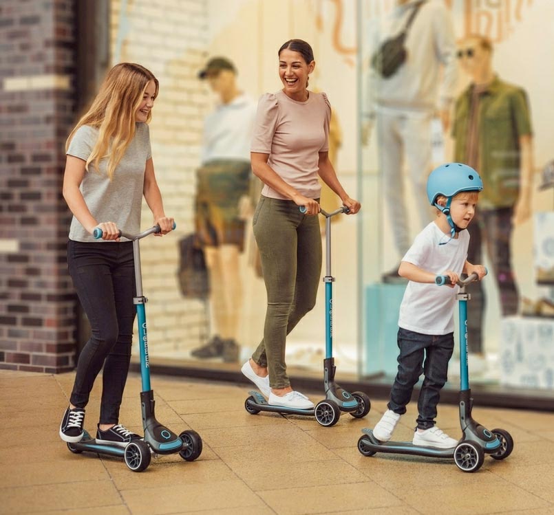 Family riding three-wheeled kick scooters together