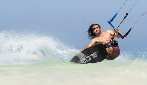 Kitesurfer carving a kite board and throwing up spray on the Ozone Code V3 kitesurfing board