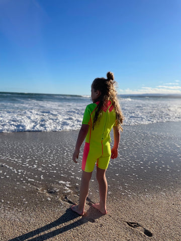 girl on beach in bright wetsuit