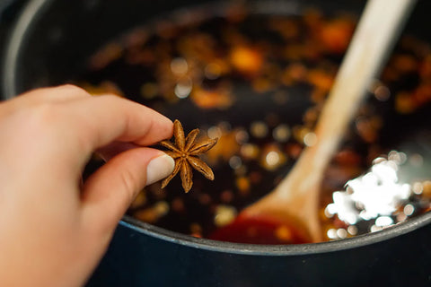 Dropping star anise into a pot of mulled wine on the stovetop