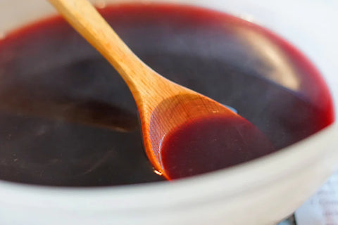 A wooden spoon resting in a bowl of red mulled wine