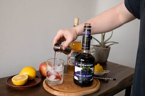 pouring creme de cassis in cocktail glass