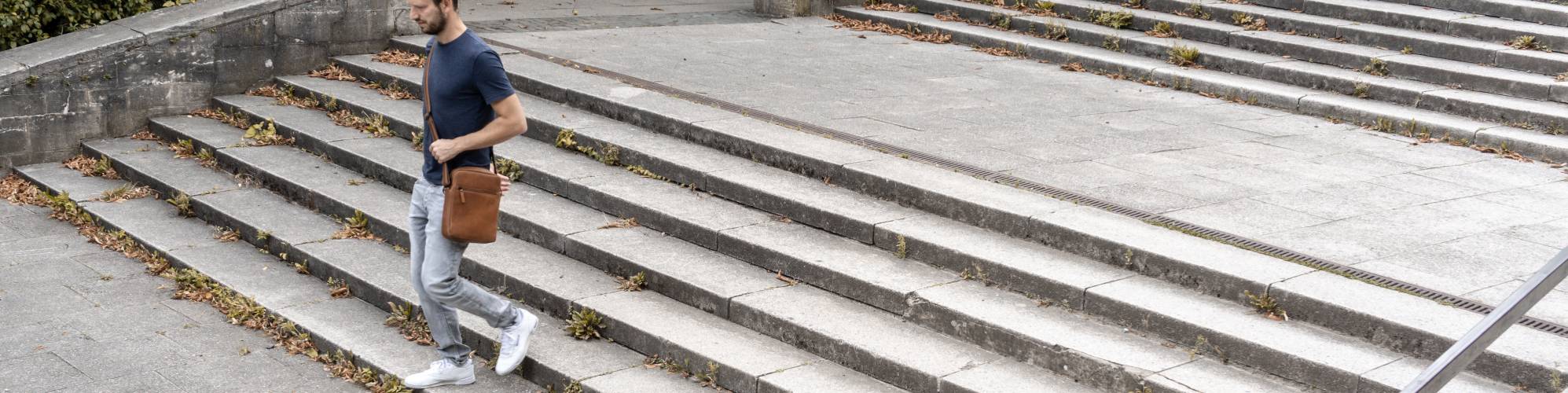 Mann auf Treppe mit Umhängetasche aus Leder