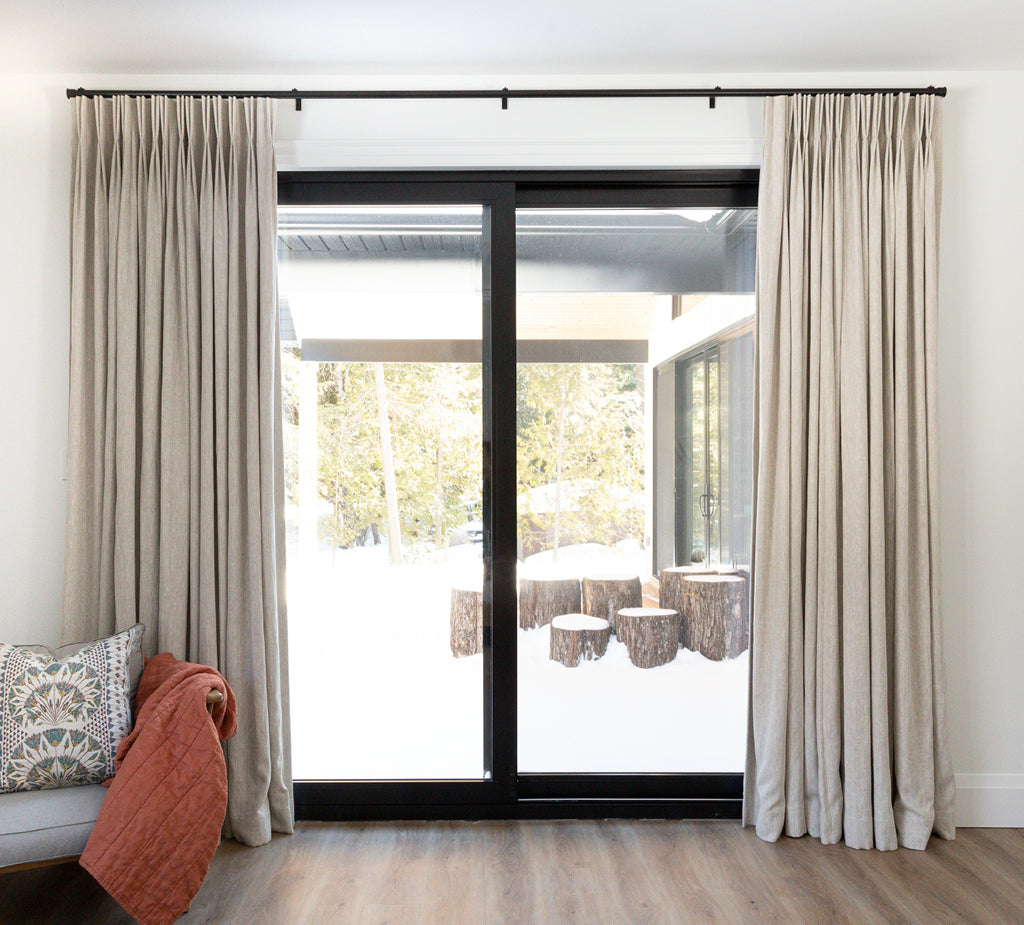 Large sliding doors leading to outside with be floor length Hemme custom beige drapes on either side.