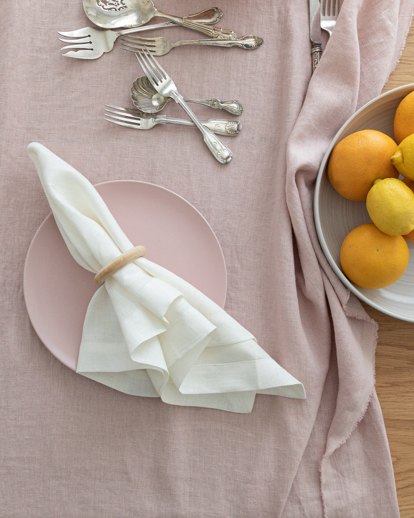 Classic white linen napkin with napkin ring holder sitting on plate and blush pink table cloth