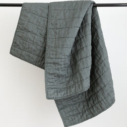 Dark green colour handmade Linen Quilt folded over black rod