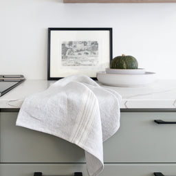 stone-washed linen tea towel is a soft, pale grey with a white stripe on counter