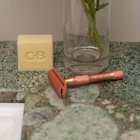 Caley-Beth Shave Balm next to a rose gold double edge safety razor on a bathroom counter.