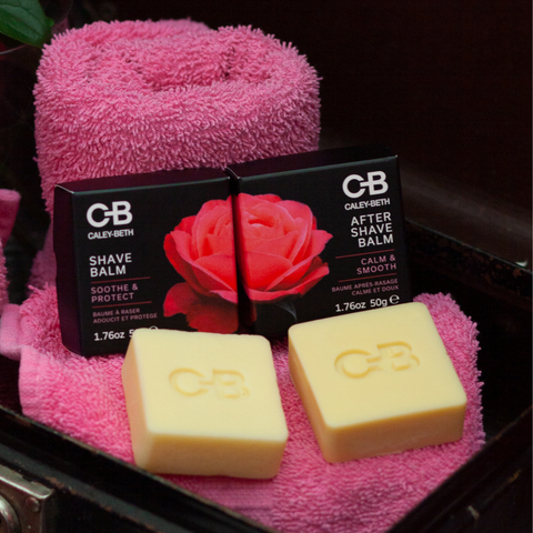 Caley-Beth Soothing Botanical Shave Balm & After Shave Balm bars resting beside their boxes on pink towels, inside an antique suitcase.