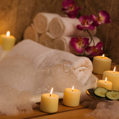 A bubble bath with a plush towel for a headrest, beautiful flowers and candle light.  